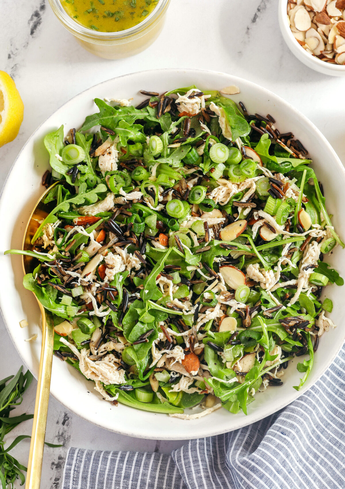 Hearty and delicious Wild Rice Chicken Salad made with leafy arugula, warm wild rice, shredded chicken, sliced almonds, and green onions all tossed with a bright lemon tarragon vinaigrette!